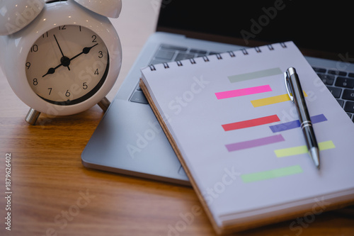 Computer laptop and calculator, alarm clock notebook with pen on wood table in appointment and business meeting, representing time management business planning concept