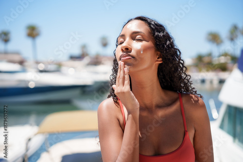 Woman applies sunscreen by the Beautiful Marina Surrounded by Boats