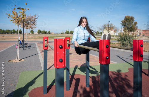 Foto Teenage girl training on parallel bars at an outdoor urban fitness park performi
