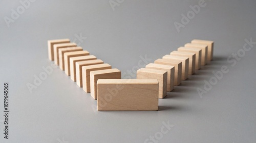Wooden dominoes falling in V shape on gray surface