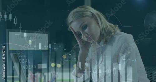 Overlaying financial data charts, businesswoman looking stressed at her workspace