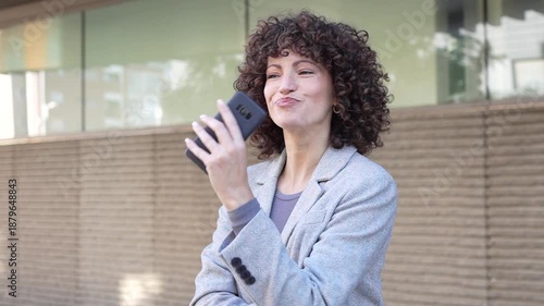 A young woman happily uses her smartphone outdoors in a busy urban area, showing modern trends