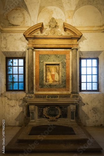 Interior view of a historic marble altar with a sacred painting and two side windows in the Cathedral of Ravenna Italy