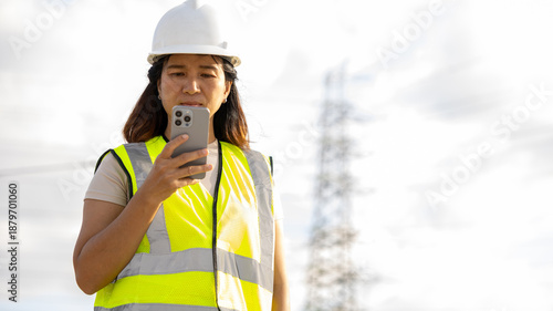 Fotografie A worker stands at a construction site wearing a safety vest and hard hat