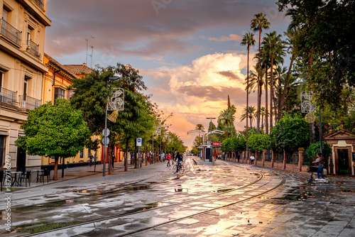 Street in Seville at sunset with palm trees and people walking, Spain, the most beautiful cities in Andalusia.