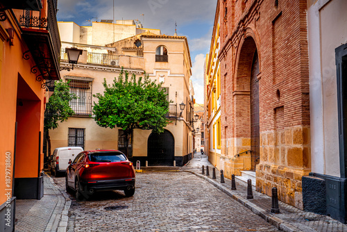 Colorful narrow streets in a Spanish city with traditional architecture and parked cars, Seville, Andalusia.