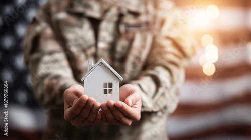 Soldier hands holding small house model, symbolizing veteran home loan, real estate investment, and military family support under an American flag
