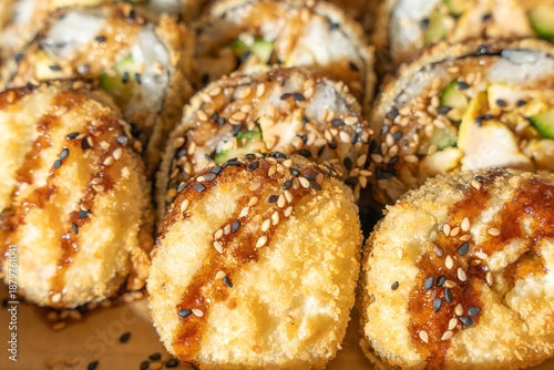 Billede på lærred Close-up of crispy fried sushi rolls topped with sesame seeds and glossy sauce