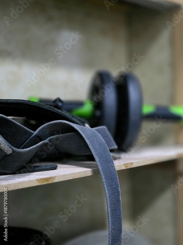 Close-up of fitness equipment: an abdominal wheel roller and an elastic resistance band on a wooden shelf.