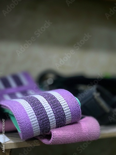 Close-up of colorful fabric resistance bands for fitness and bodybuilding on a wooden surface.