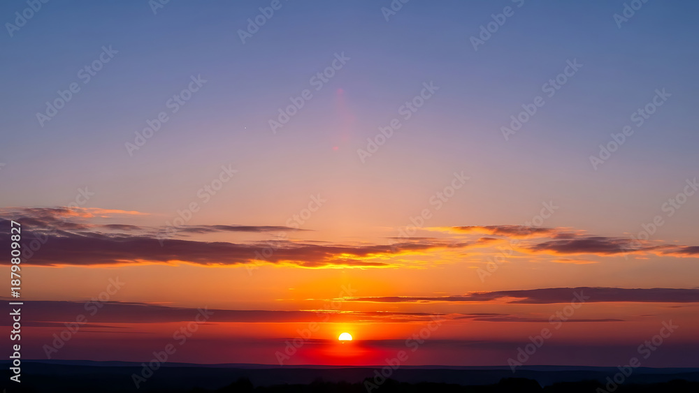 Fototapeta premium Vibrant sunset over vast horizon with colorful sky and glowing sun