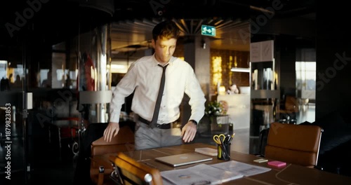 A young professional adjusts his attire, readying himself for an important meeting in a stylish office space