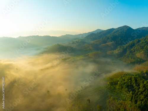 Aerial view of flowing fog waves on mountain tropical rainforest,Bird eye view image over the clouds Amazing nature background with clouds and mountain peaks in Thailand