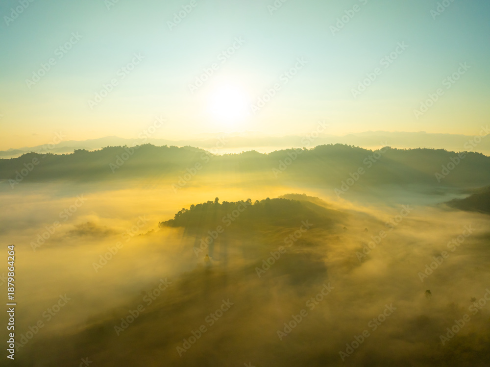 Obraz premium Aerial view of flowing fog waves on mountain tropical rainforest,Bird eye view image over the clouds Amazing nature background with clouds and mountain peaks in Thailand