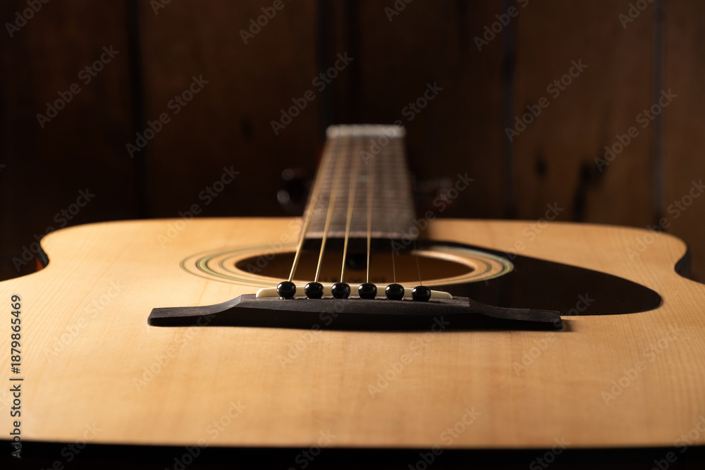 Fototapeta premium Close-up acoustic guitar, focusing on the strings, bridge, and smooth wooden body.