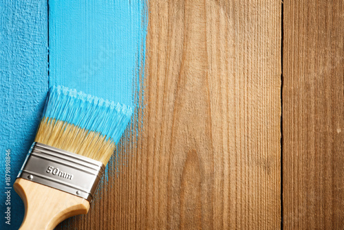 Bright blue paint being applied with a brush on wooden surface, highlighting fresh color coating, home improvement, renovation, and creative DIY project with natural wood texture contrast.