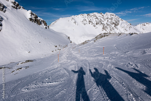 Skiers shadow on the ski slope in snow and beautiful winter landscape in Swiss Alps, Ski region Arosa-Lenzerheide
