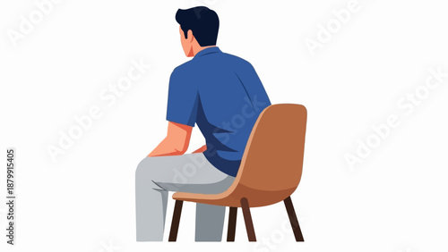 A man in a blue shirt and grey pants sits on a brown chair, facing away