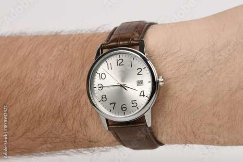 Classic silver analog wristwatch with brown leather strap on male wrist