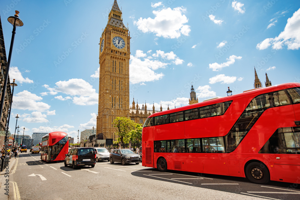 Fototapeta premium Red double-decker buses traveling past Big Ben in London, UK