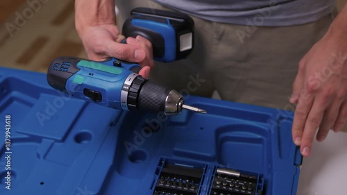 Wallpaper Mural Organizing drill and accessories, Person assembling cordless drill with accessories, Detailed view of organizing and preparing cordless drill with bits and battery for use Torontodigital.ca