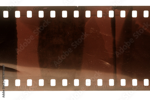 Dusty and grungy 35mm film texture or surface. Perforated scratched camera film isolated on white background.