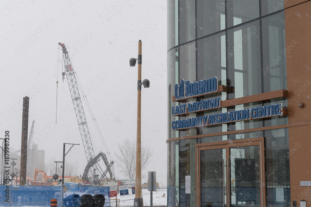 Fototapeta premium construction site and sign outside East Bayfront Community Recreation Centre located at 261 Queens Quay E, during a snow storm on 2026-01-15 in Toronto