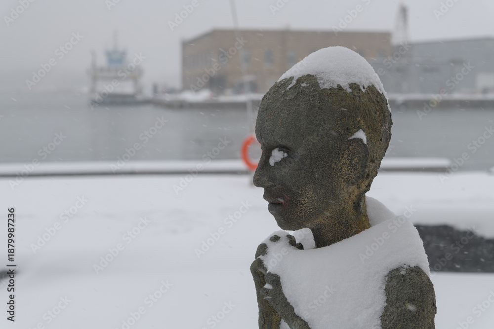 Fototapeta premium close-up of Child Emigrant created by Irish artist Rowan Gillespie part of The Arrival, set beside the old Canada Malting silos on Eireann Quay, Toronto, during winter storm on 2026-01-15