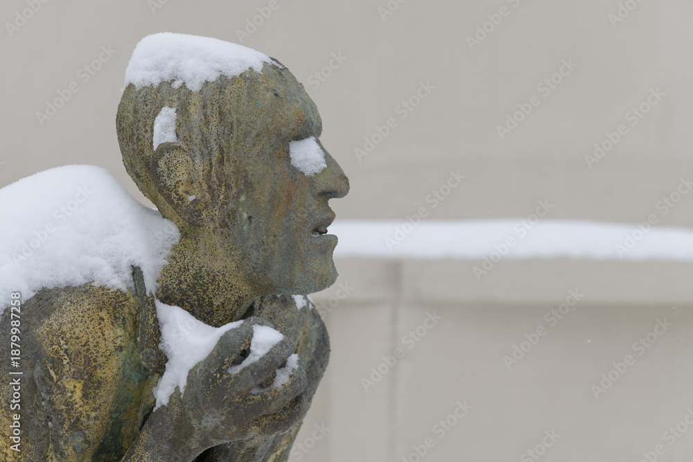 Fototapeta premium right profile of Apprehensive Man created by Irish artist Rowan Gillespie part of The Arrival, set beside the old Canada Malting silos on Eireann Quay, Toronto, during winter storm on 2026-01-15