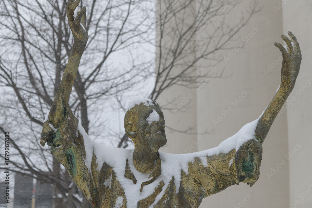 Fototapeta premium front of The Jubilant Man created by Irish artist Rowan Gillespie part of The Arrival, set beside the old Canada Malting silos on Eireann Quay, Toronto, during winter storm on 2026-01-15