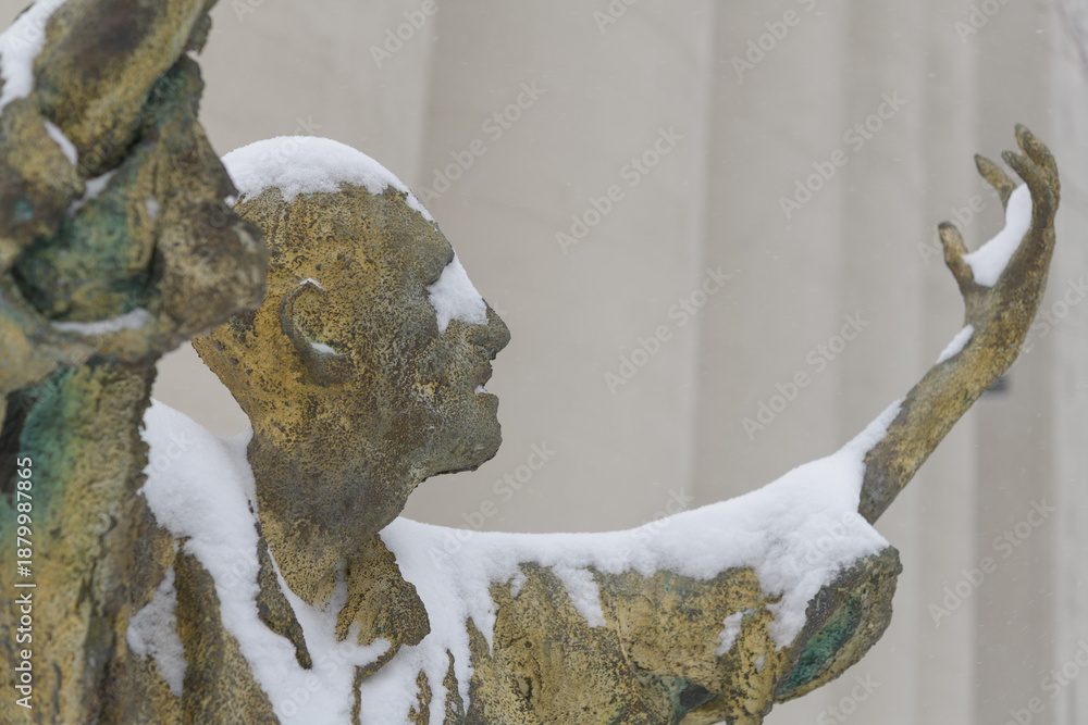 Fototapeta premium The Jubilant Man created by Irish artist Rowan Gillespie part of The Arrival, set beside the old Canada Malting silos on Eireann Quay, Toronto, during winter storm on 2026-01-15