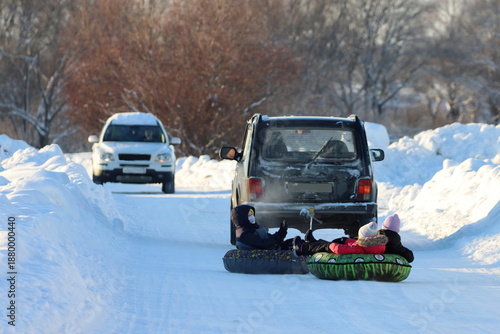 In winter, it is unsafe for children to ride on inflatable sleds attached to a car on a snowy public road. Snow tube