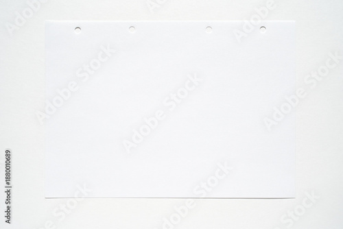 Foto Blank white sheet of notebook paper with four punch holes on light background