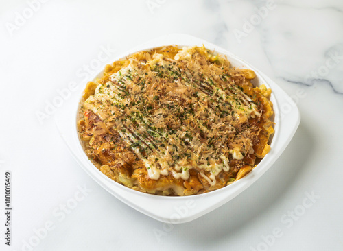 Okonomiyaki Delicious takoyaki dish with bonito flakes and saucein bowl on a clean white marble surface