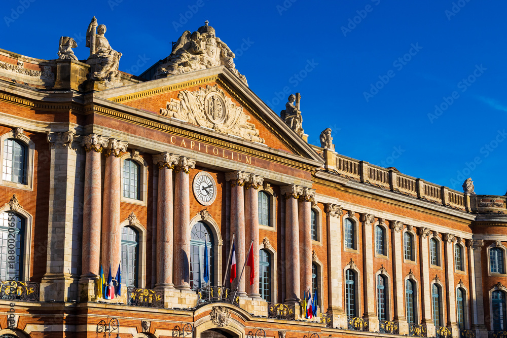 Obraz premium Façade of the Capitole, Toulouse city hall, illuminated by the sun in front of dark silhouettes