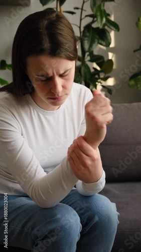 Wallpaper Mural Sad young woman suffering pain on hands and fingers, arthritis inflammation. Upset caucasian female has pain in wrist sitting on couch at home. Health care and medical concept Torontodigital.ca