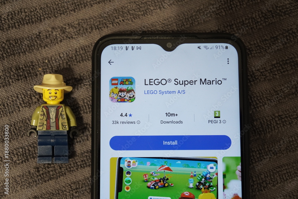 Obraz premium LEGO Super Mario app displayed on a smartphone next to a LEGO minifigure