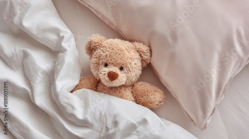 Cute teddy bear tucked in bed with white sheets and blush pink pillow for cozy sleep