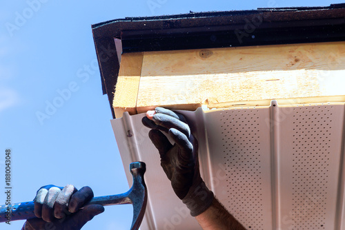 Working on roof installation with PVC soffit panel at construction site