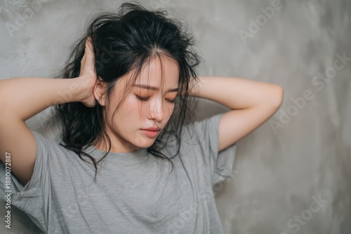 Close up of a young Asian woman with anemia induced dizziness hands behind her head