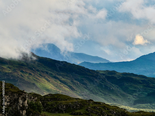 Rolling hills stretch into the distance, partially veiled by low clouds and morning haze.