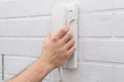 Wallpaper Mural A man's hand lifts a white intercom telephone Torontodigital.ca
