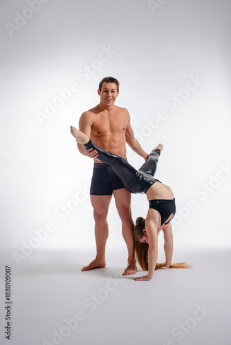 Wallpaper Mural Athletic couple performs acro yoga. A muscular man spots a flexible woman doing a handstand split in a studio. Torontodigital.ca