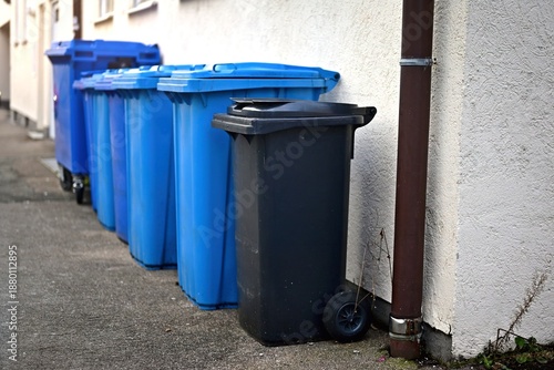 Trashcans  standing at the roadside ready for collection and emptying. 