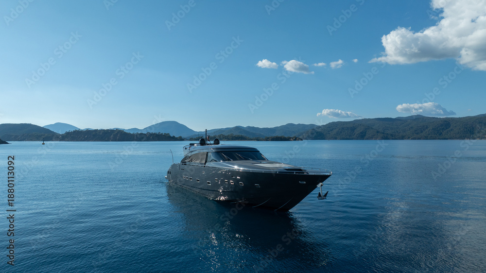 Obraz premium Luxury Yacht on Serene Waters: A sleek, modern yacht cruises effortlessly on calm, crystal-clear waters, reflecting the bright blue of the sky and offering a vision of pure luxury and tranquility.