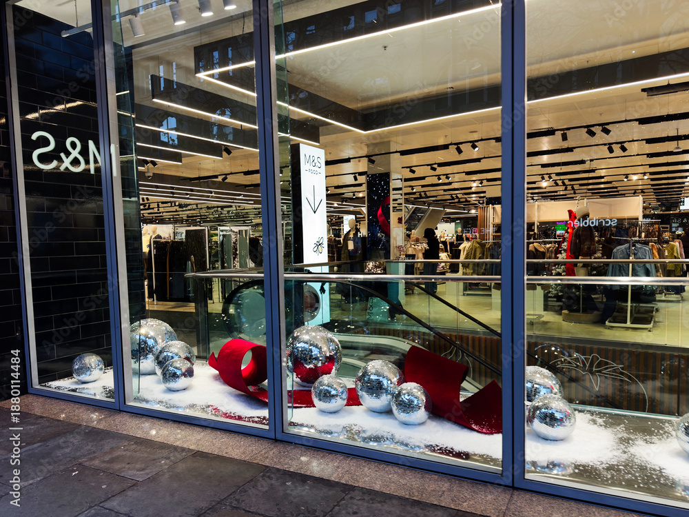 Obraz premium Shop window Marks and Spencer display with festive decor and shoppers inside a Manchester store UK