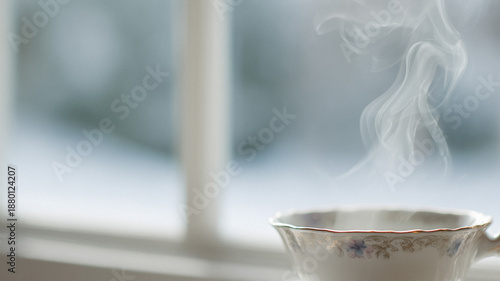 Steaming hot tea in vintage porcelain cup, warmth and comfort on a cold winter day by the window