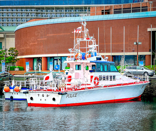 Japanese Police Patrol Boat Docked at Urban Harbor with Modern Architecture and National Flags