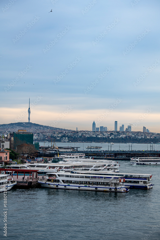 Fototapeta premium Istanbul, Turkey - January 05, 2026: Passenger ferries docked at the Karakoy terminal with a distant view of the Camlica Tower and Uskudar district