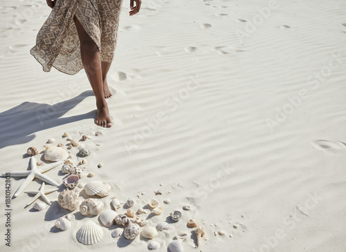 Barefoot person walking on a pristine tropical white sand beach with seashells